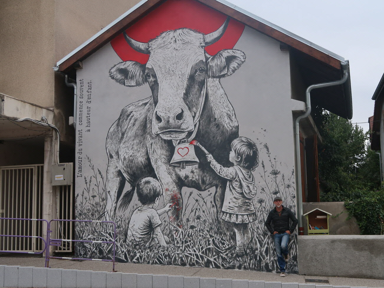 Fresque de l'artiste Mö sur la Grande-Rue de Reignier-Ésery : une vache monumentale et deux enfants dans les herbes hautes